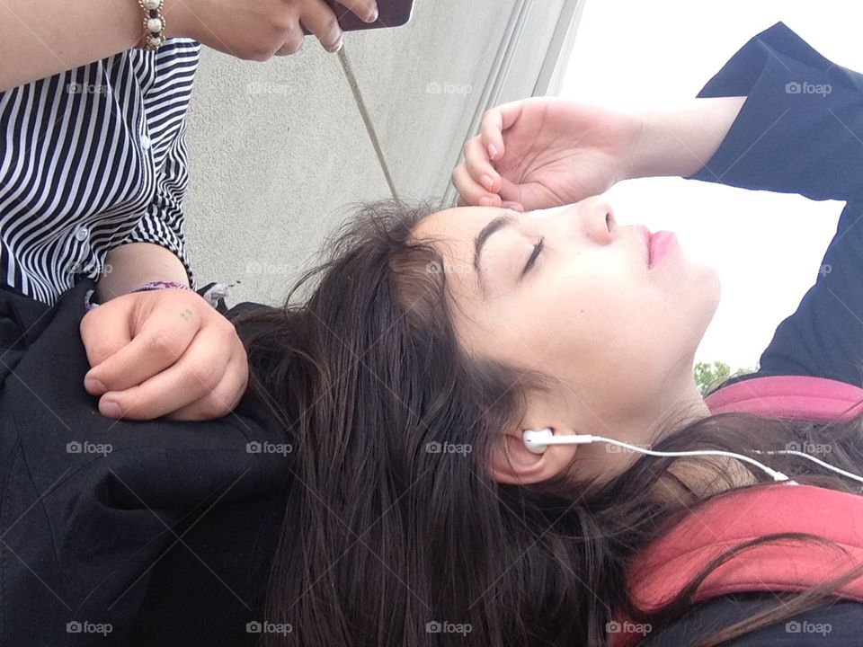 girl laying down with headphones in and eyes closed, profile view