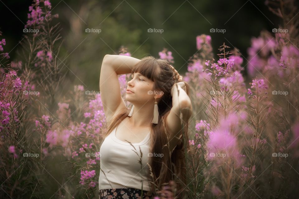 Beautiful young woman in a field of blossom flowers in boho style
