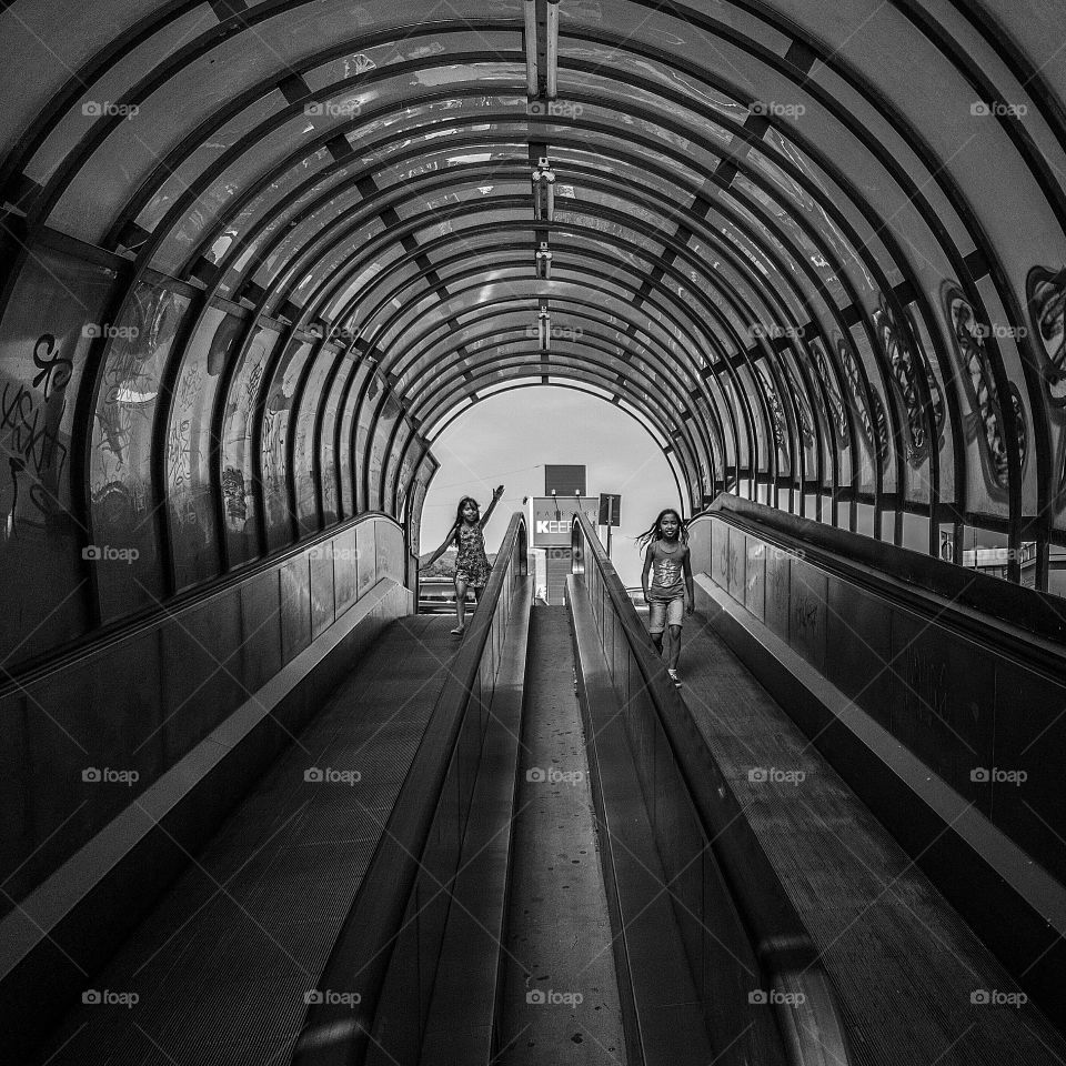 Two little girl on escalator in station