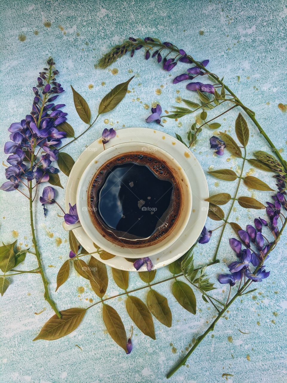 Background of a cup of hot coffee on the table with beautiful flowers close-up. Top view.