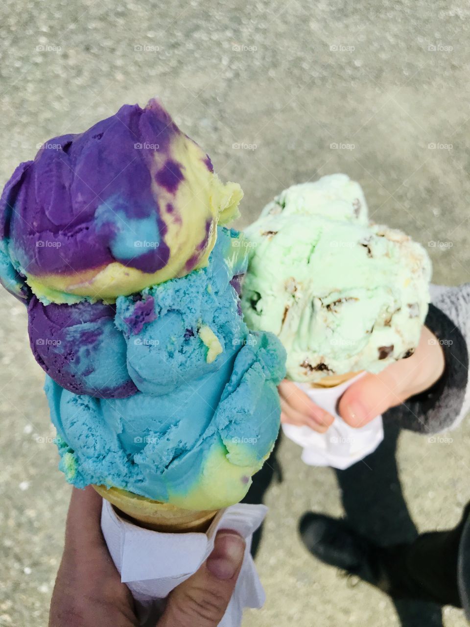 Two ice cream cones.blue yellow purple moon mist and green mint chocolate chip. 