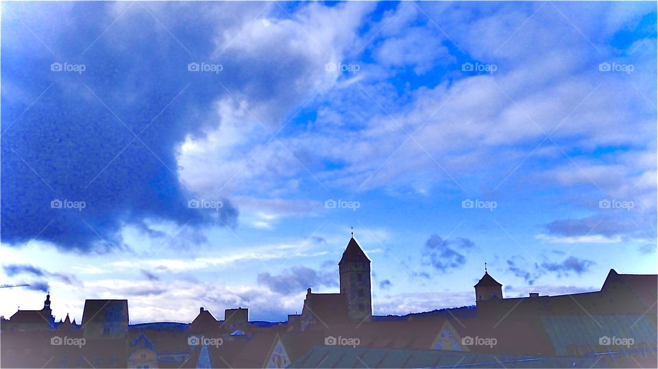 Dark blue evening skies and impressive curves in the cloud formations over the silhouette of the city of Regensburg, Germany with its traditional European architecture including churches with rhombic towers and steeples. The photo was taken in 2019.