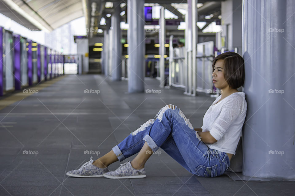 Asian women sit on the floor Background blurry Skytrain station.