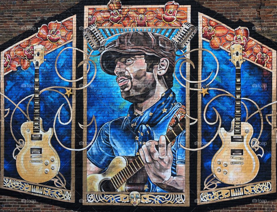 Wall art mural of musician on old brick building. Beautiful colorful paintings.