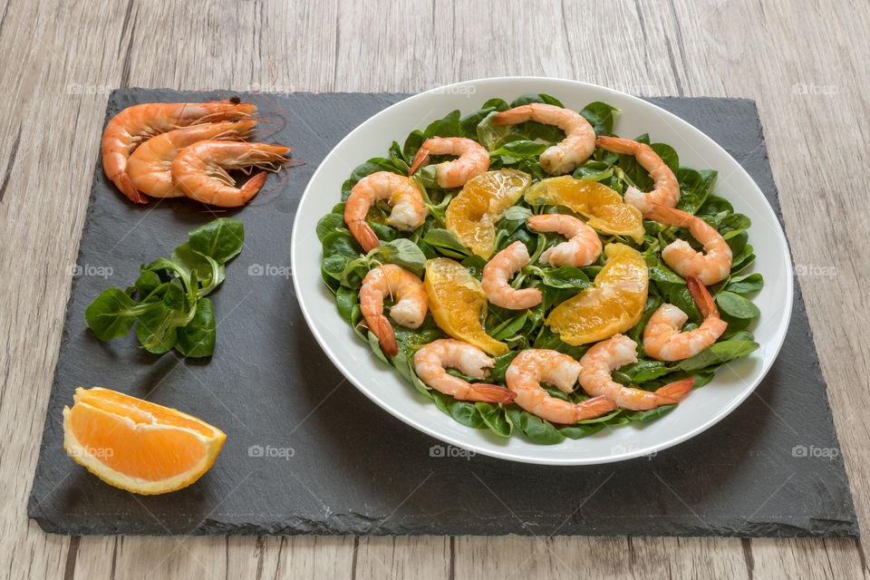an homemade summer salad made with lamb lettuce, orange wedges and prawns.