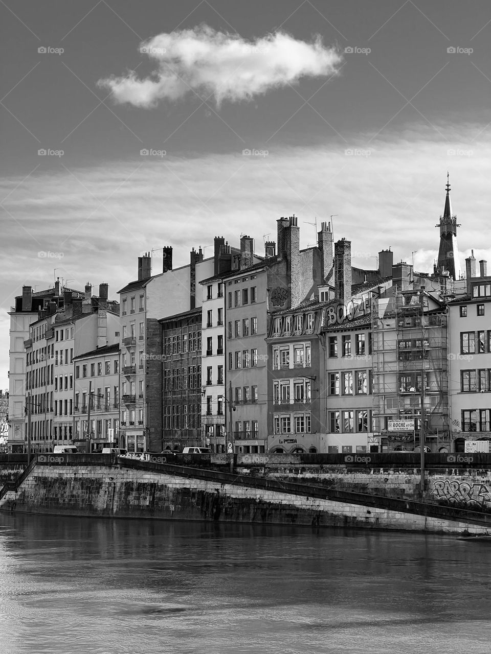 Black and white picture of an old city overlooking the river under a beautiful cloudy sky 