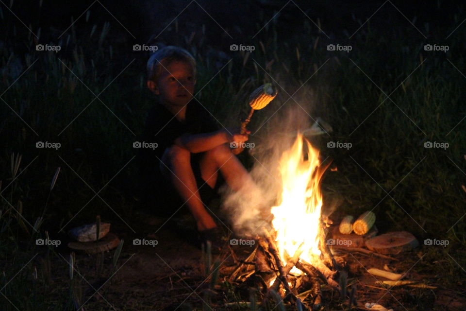 boy cooking corn with fire