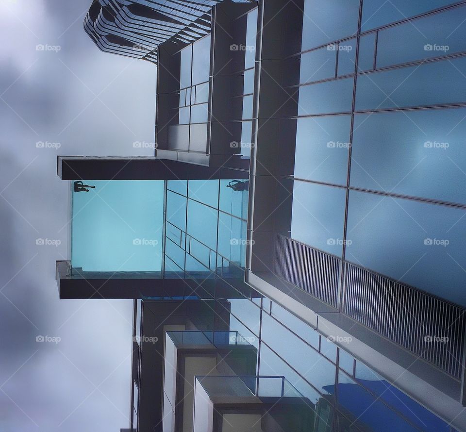 Person in a swimming pool jutting out from a luxury condominium building