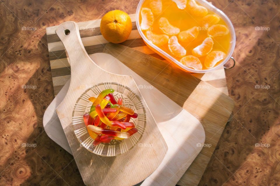 Delicious orange jelly with tangerine slices in a container and jelly worms.