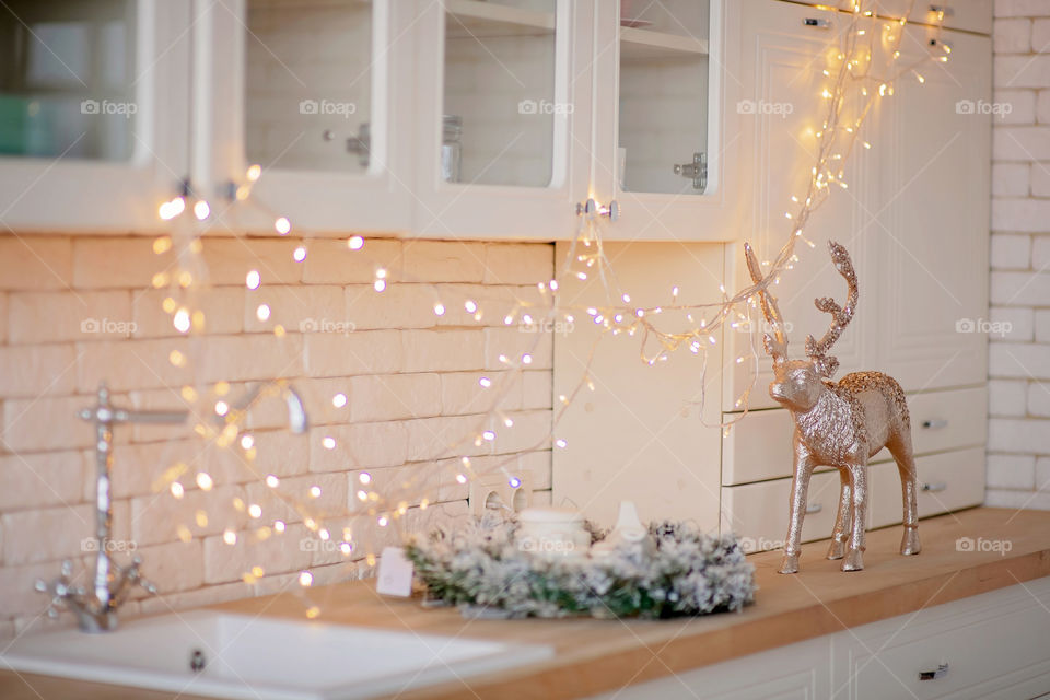 Festive winter cozy kitchen interior with garlands, decorations and gifts.  Christmas dinner at the decorated table.