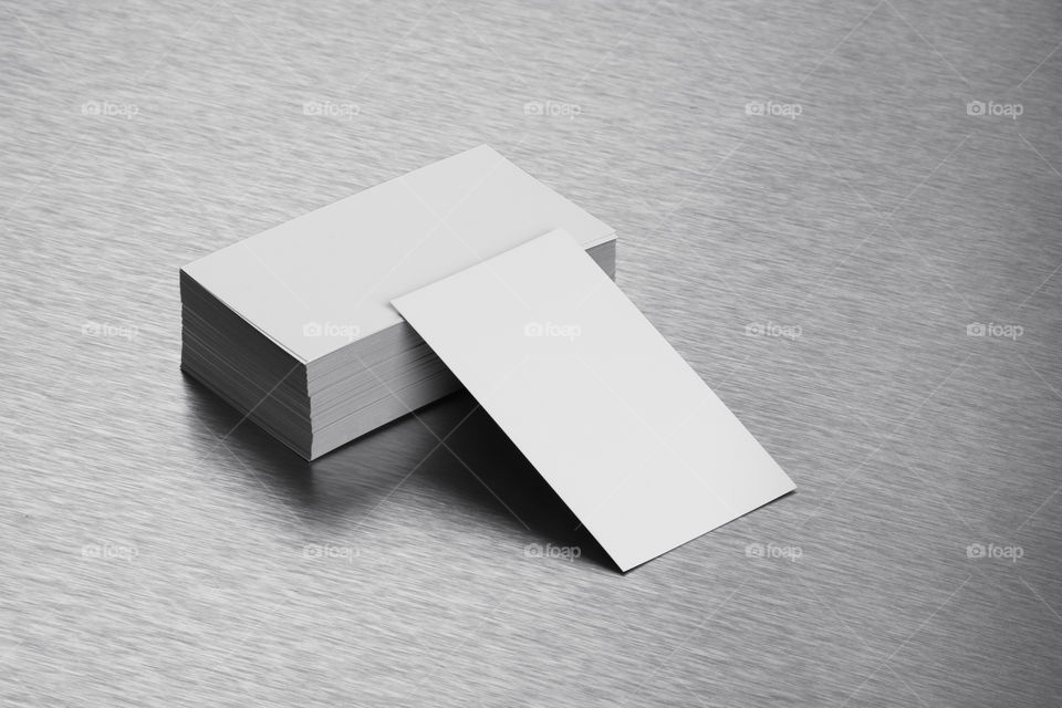 Blank white business cards on brushed steel background