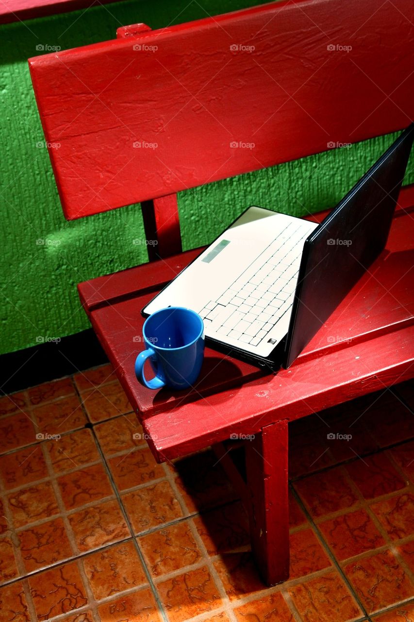 coffee mug and laptop computer on an outdoor bench