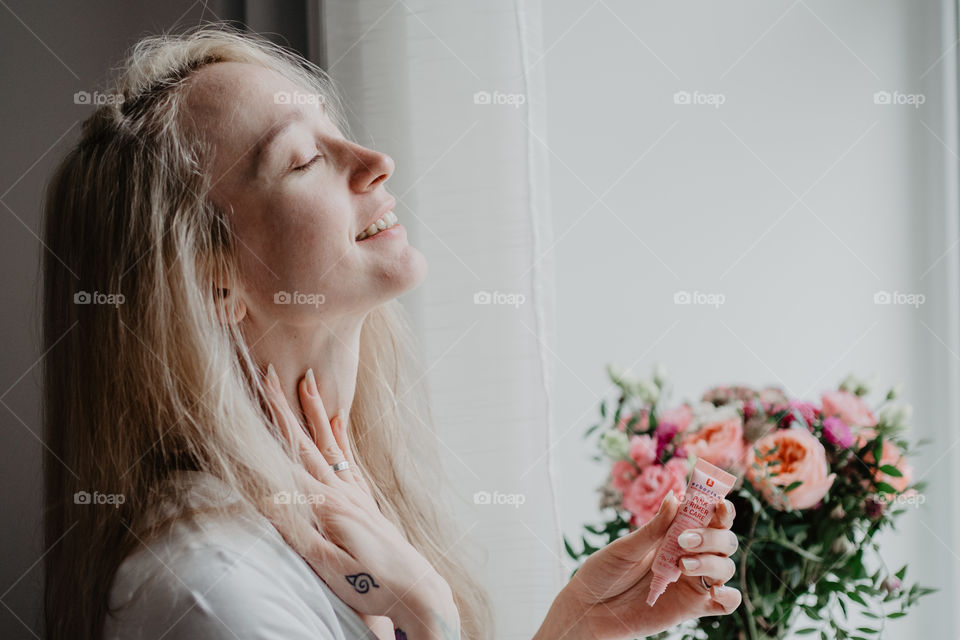smiling woman using skin care product