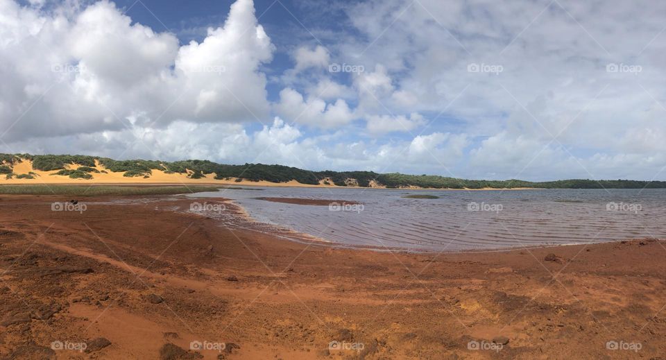 Lake surrounded by a red ground and the sand dunes in the hot 