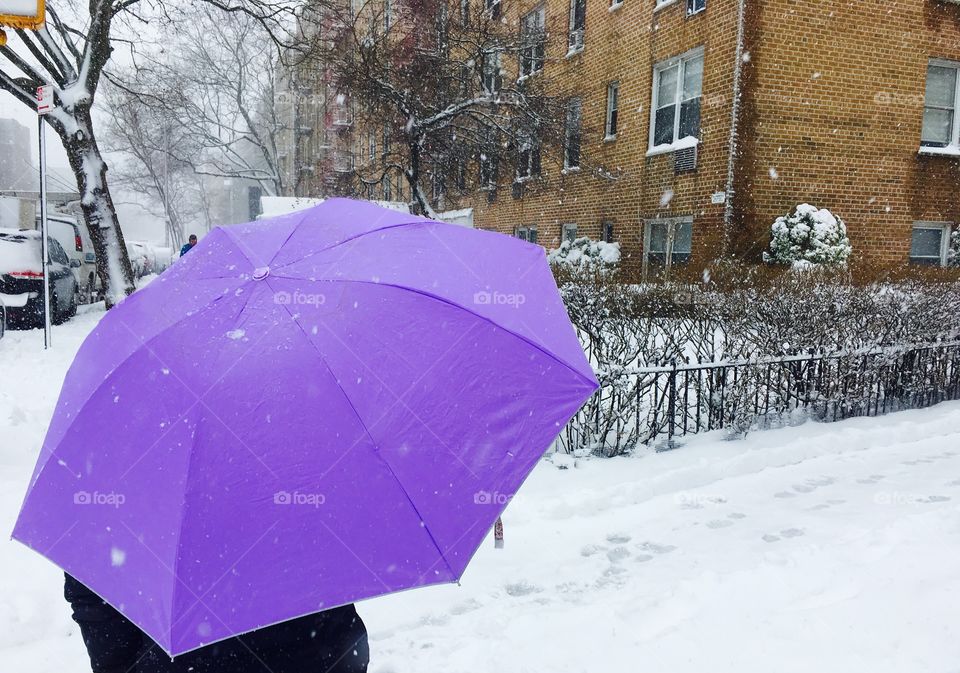 Person standing on snow holding umbrella