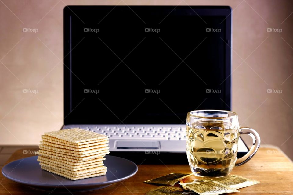 soda crackers, cup of tea and laptop computer