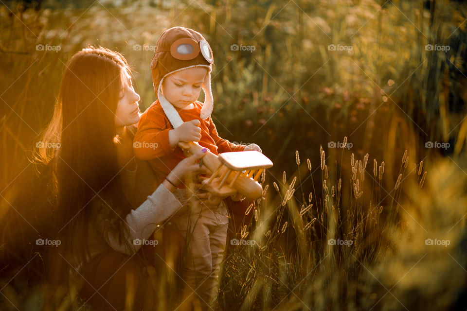 Mother and son with wooden plane at sunset