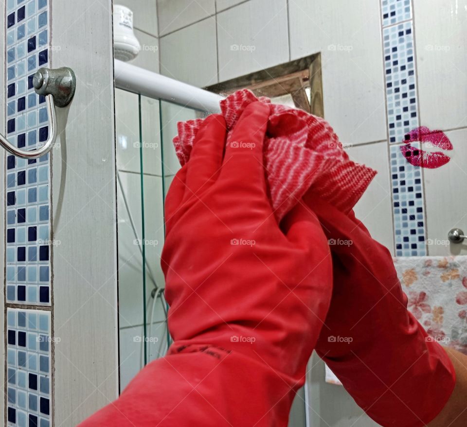 Mirror cleaning with red rubber gloves with lipstick mark