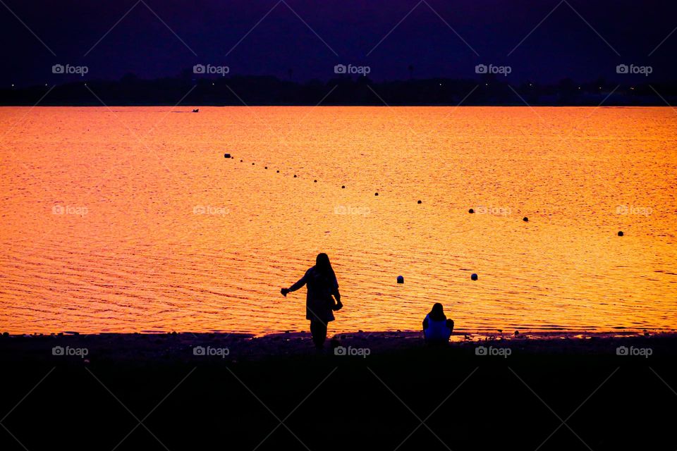 Playing by the lake at sunset. Viewing the beautiful golden hour at sunset