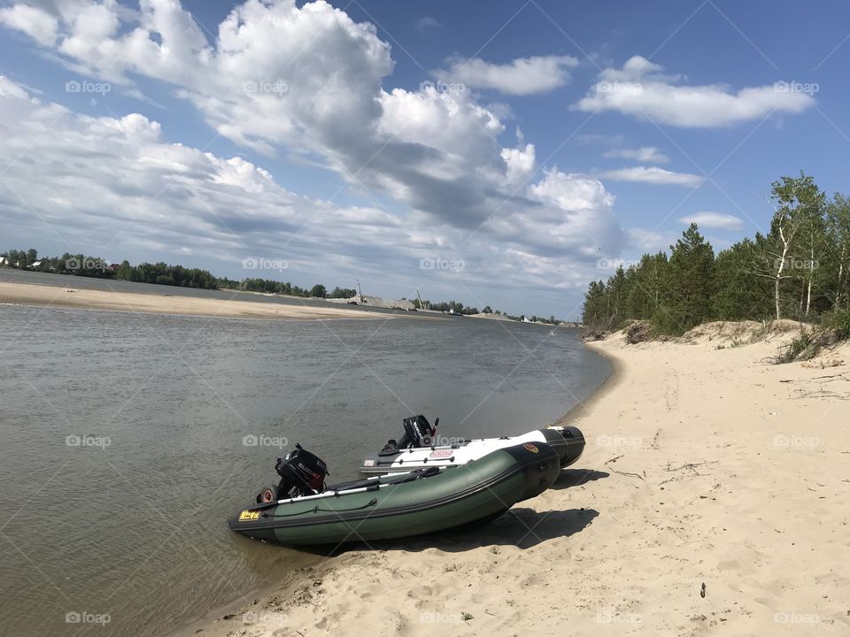 Inflatable boats on the river. The nature of Russia.  Suzuki Motors.  Sunny day on the river. White and green boat. It’s summertime! Big white clouds. River and sky.