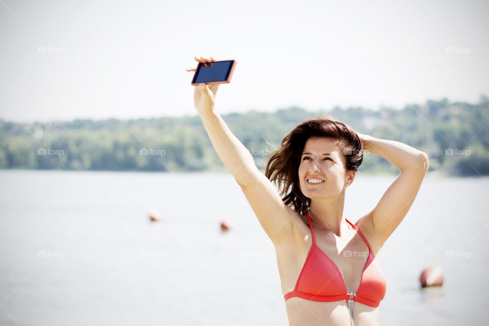 Woman in bikini taking selfie in lake