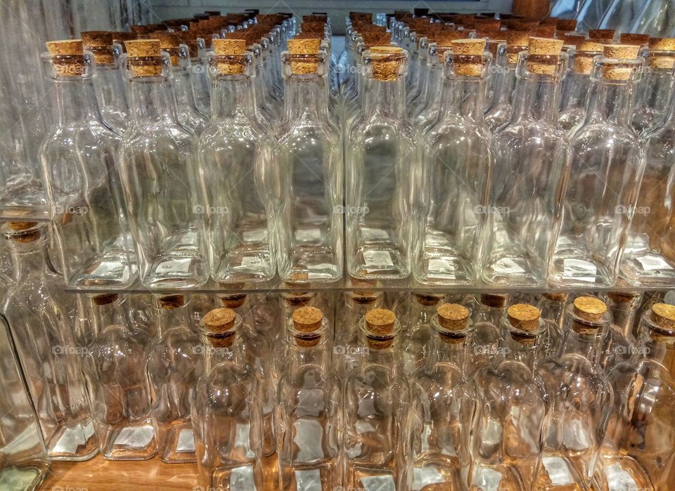 Many glass bottles standing in a row with cork cap to close in a shop