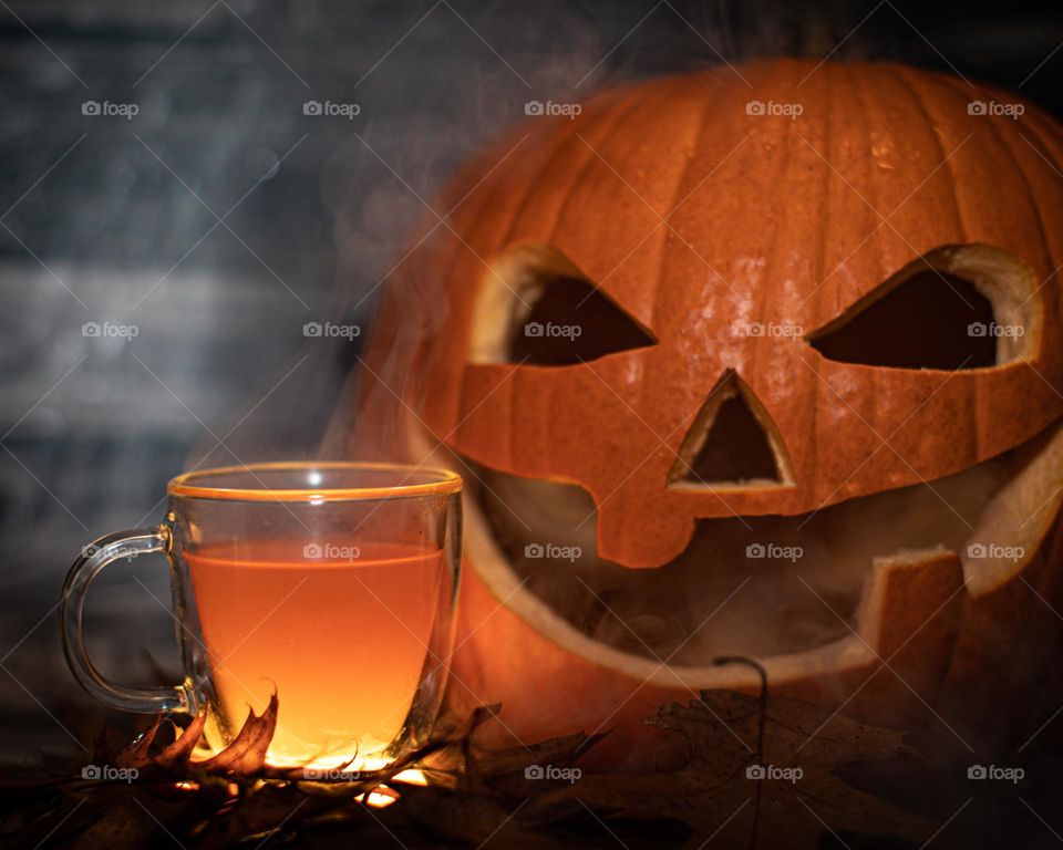 Glowing hot cider with a carved pumpkin and a spooky setting