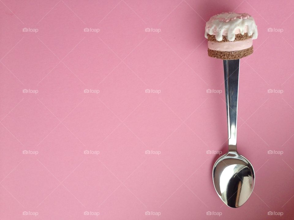 Spoon with cup cake on top on pink background 