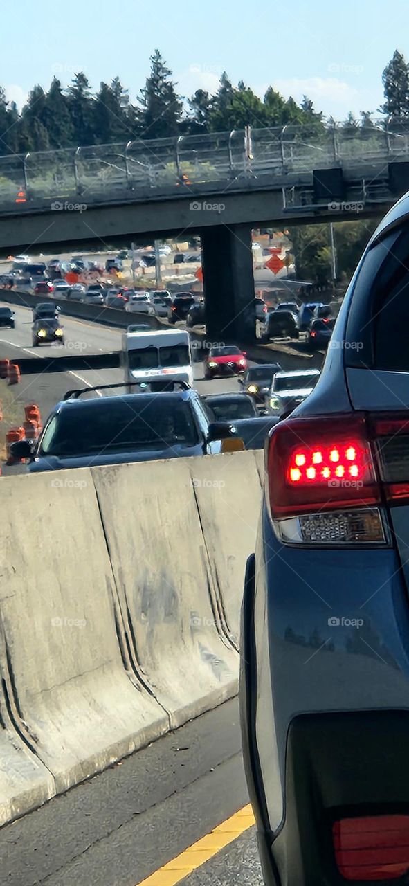 photo of a red car tail light and on-coming commuter traffic in Oregon taken by a passenger in a vehicle behind it