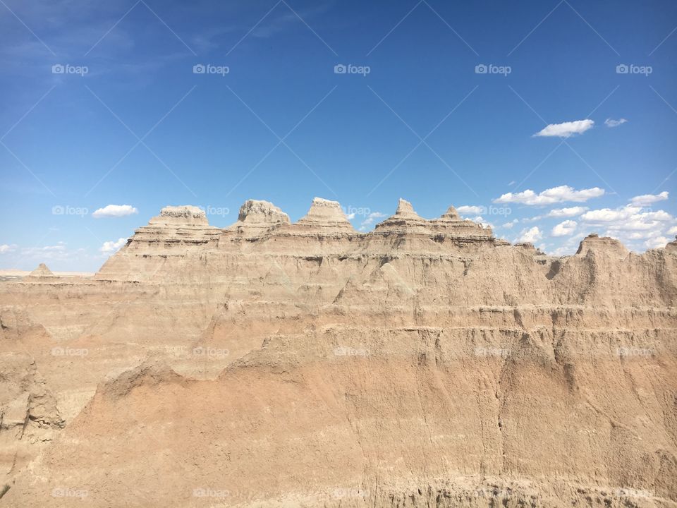 Badlands, where rock touches the blue skies and white clouds linger. Love the rock texture and the various lines and degrees of rock