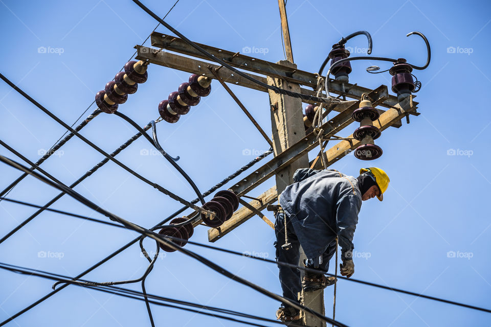 Electrician working on the electricity pole to replace the electrical insulator