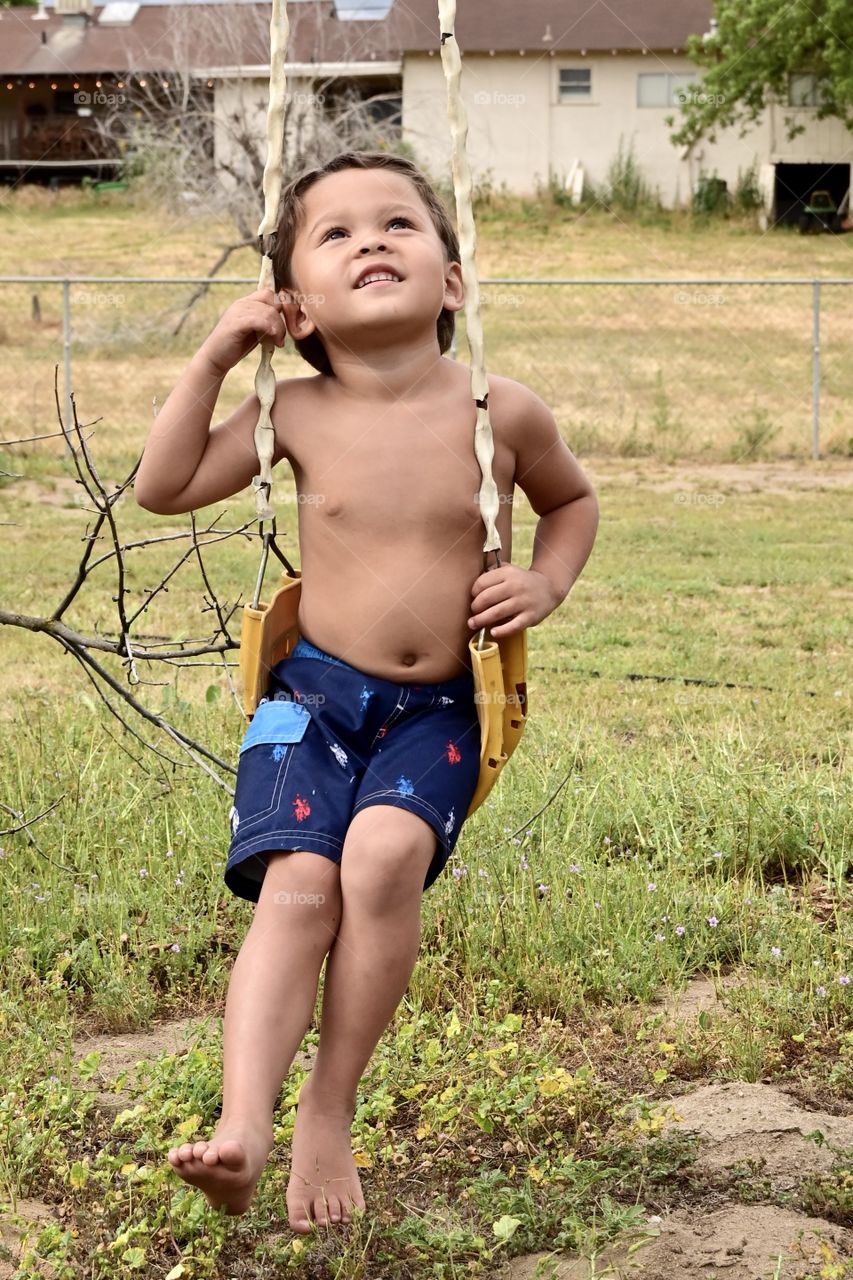 Close up shot of a boy on the swing in summer 