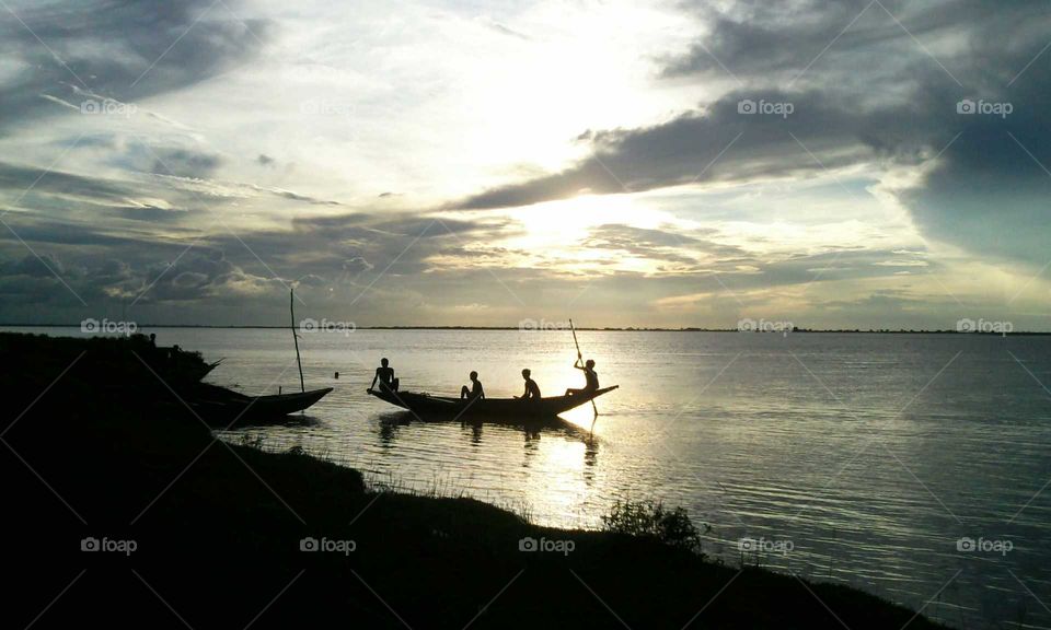 Four men in a boat.. Beautiful sun set