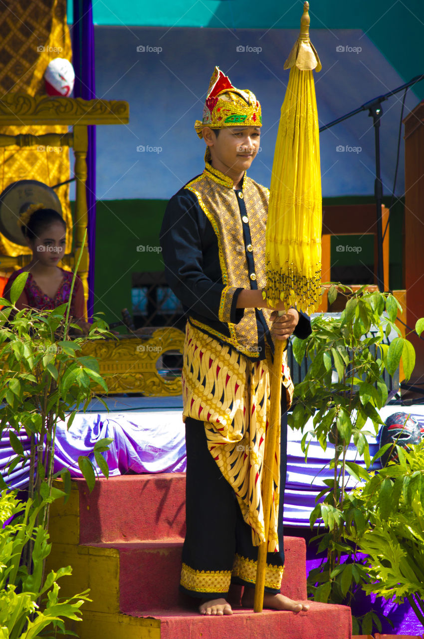 Male young performer standing with yellow umbrella