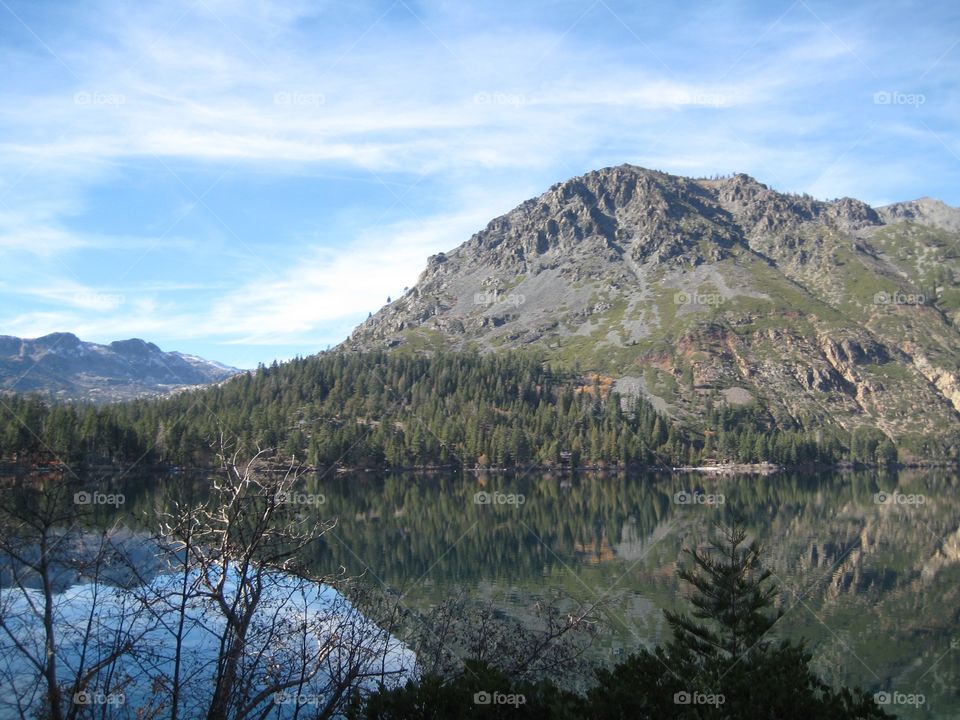 Reflection in lake. Still lake waters reflecting trees and hill