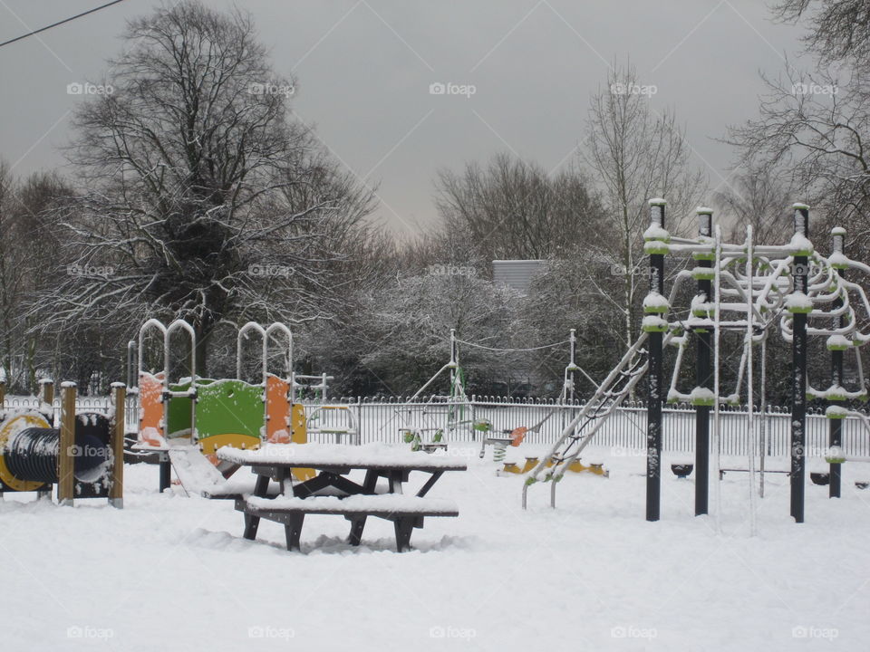 colourful play equipment in the park covered in snow