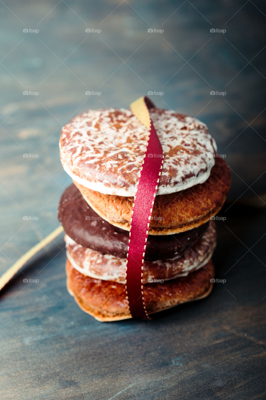 A few gingerbread cookies wrapped in red ribbon Happy Christmas on wooden table. Plain background. Portrait orientation