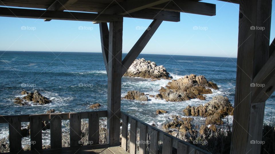 California Coast view of Ocen waves breaking on rocks from wooden structure