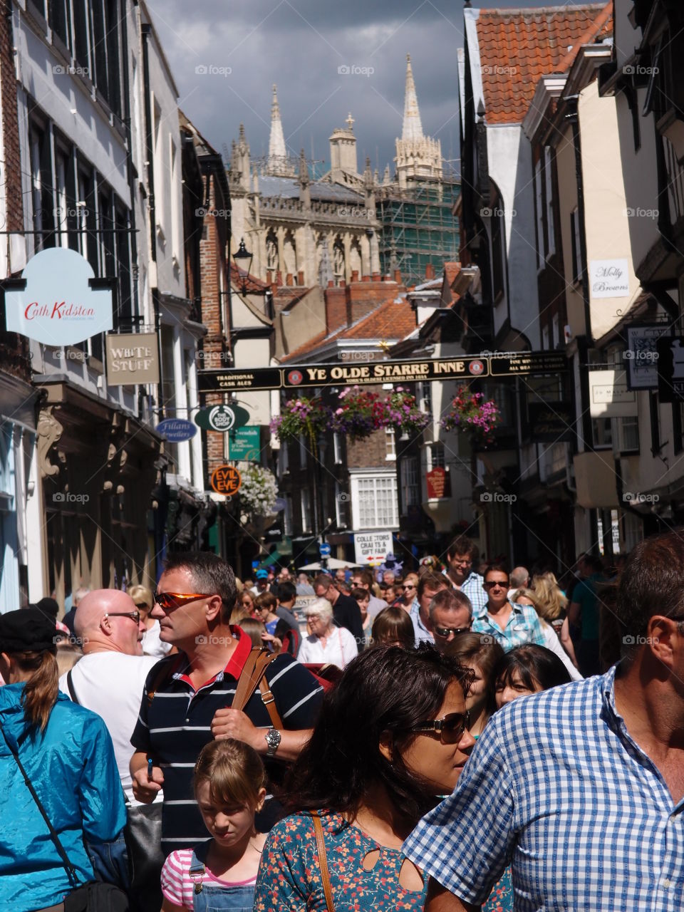 Crowds of people walking through shopping districts in An English town on a sunny summer day. 