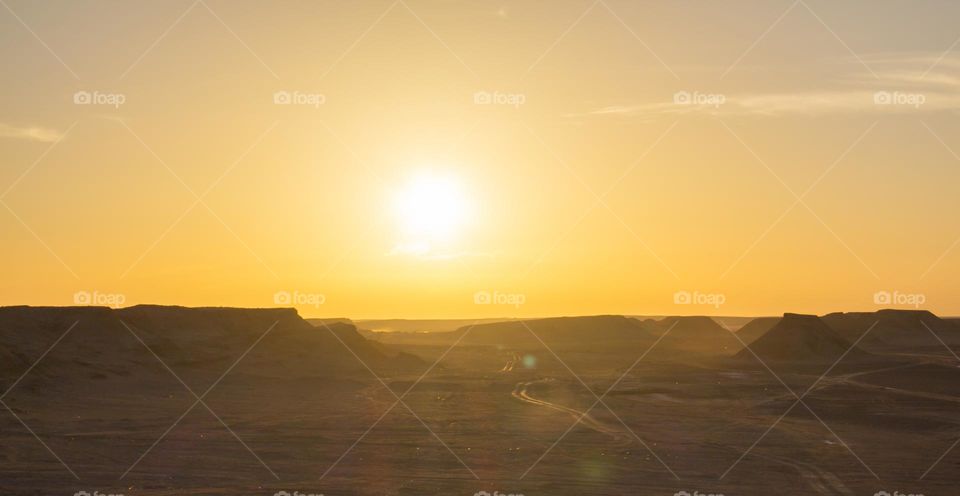 Mountain against the backdrop of the setting sun in the Sahara desert.