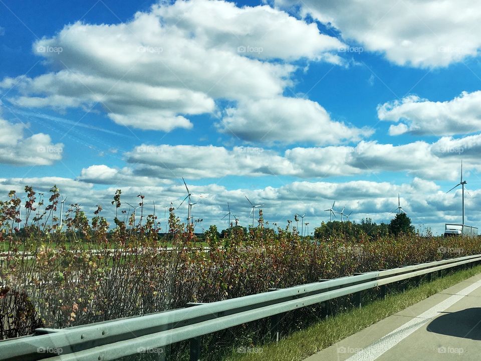 The side of a highway in Germany with dramatic, high contrast clouds in a deep blue sky. 