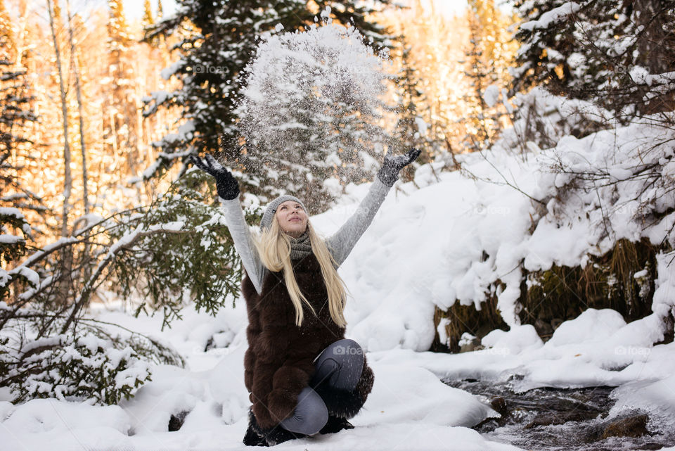 Happy woman throwing snow in winter