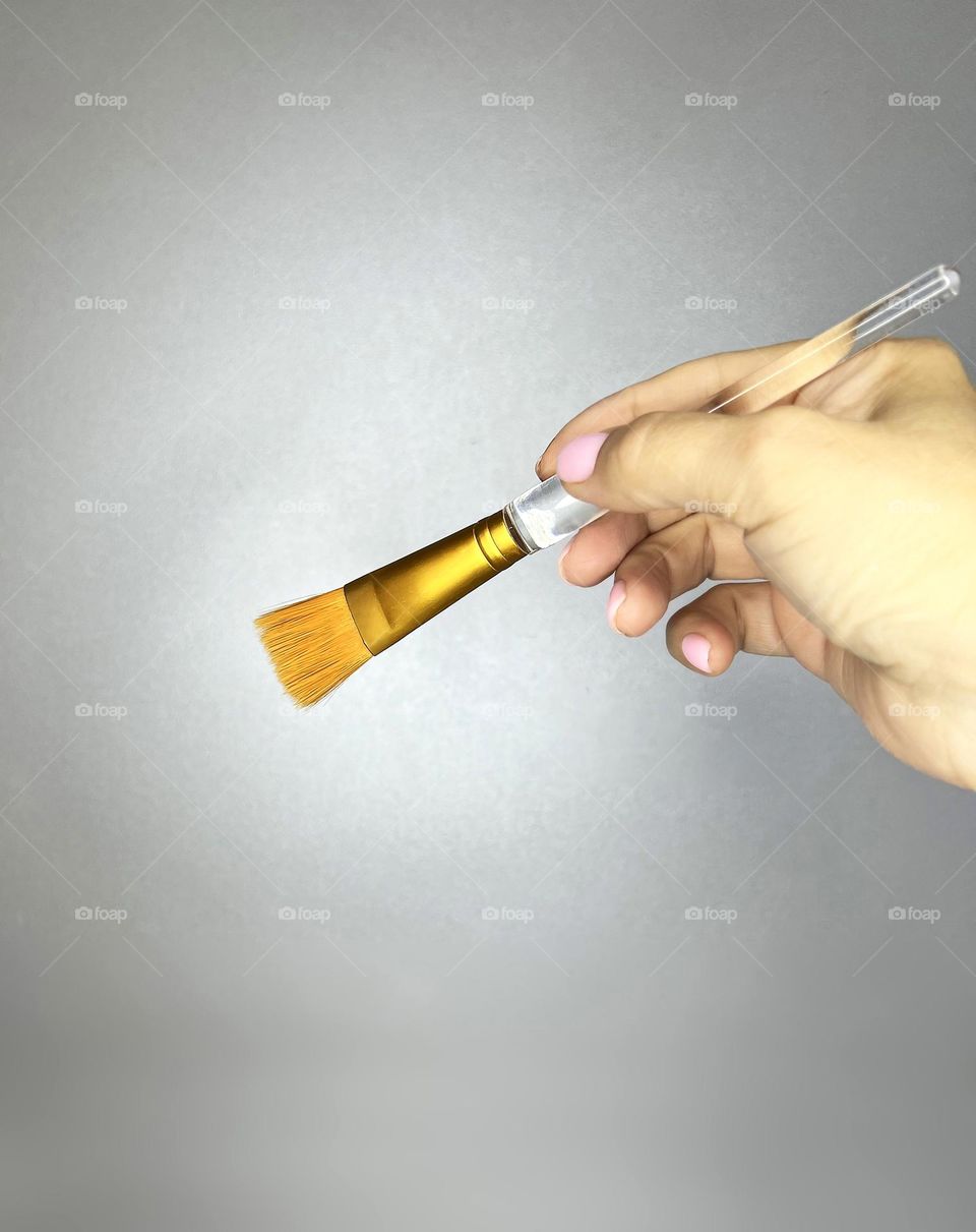 Female hand with cosmetic brush close-up on grey background