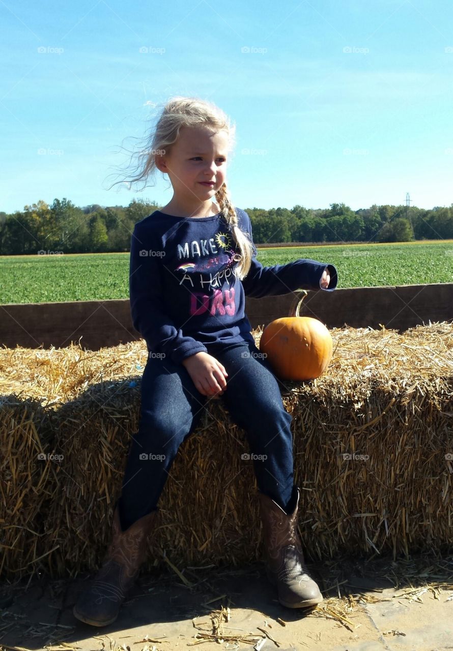 Smiling girl sitting near pumpkin