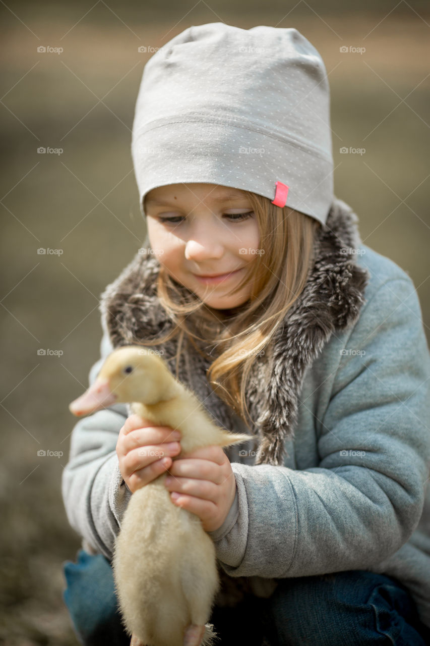 Cute Little girl with duckling outdoor portrait 