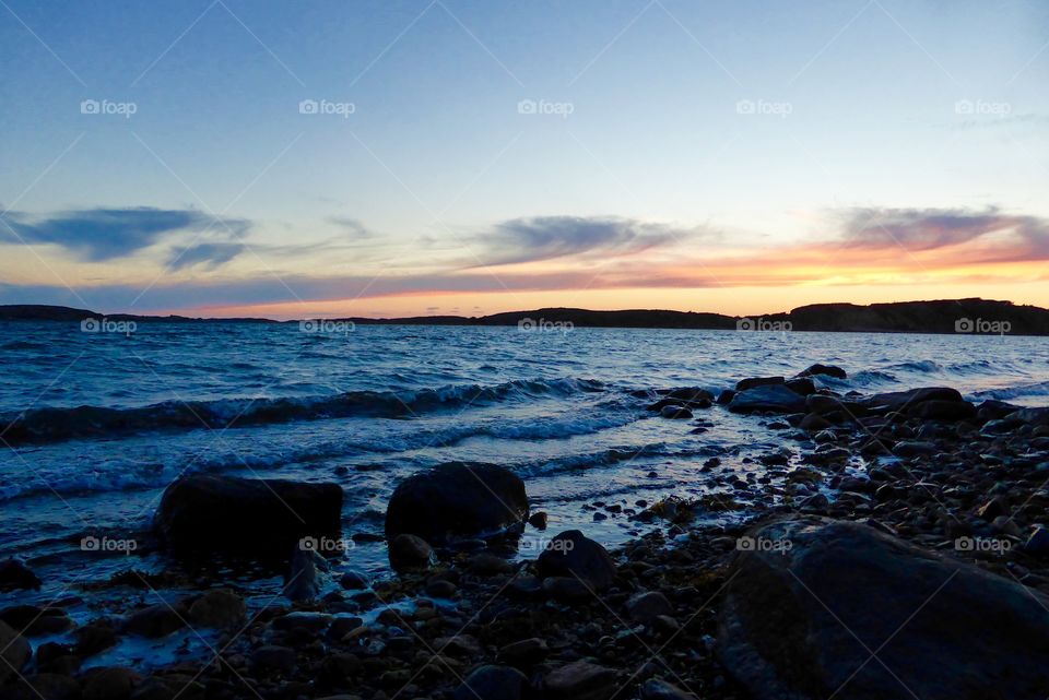 Black rocks on the beach in the sunset