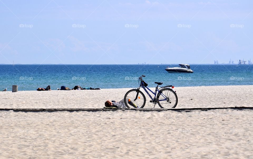 liyng on the beach near bicycle at the baltic sea coast in Gdynia, Poland.