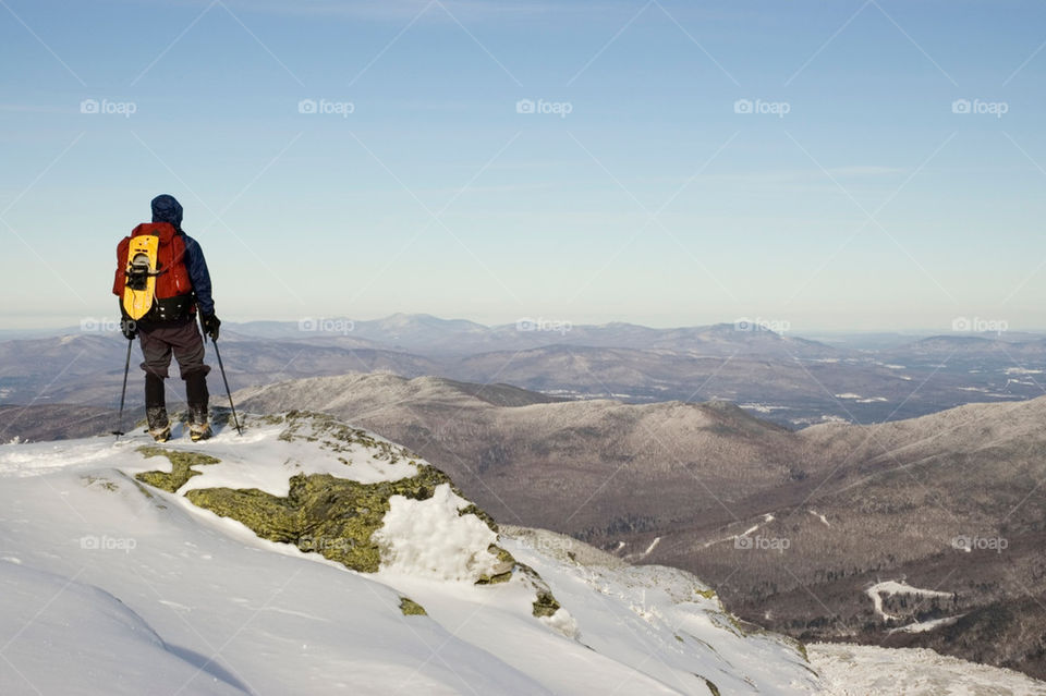Man stand atop mount Mansfield VT and admired the view in winter.