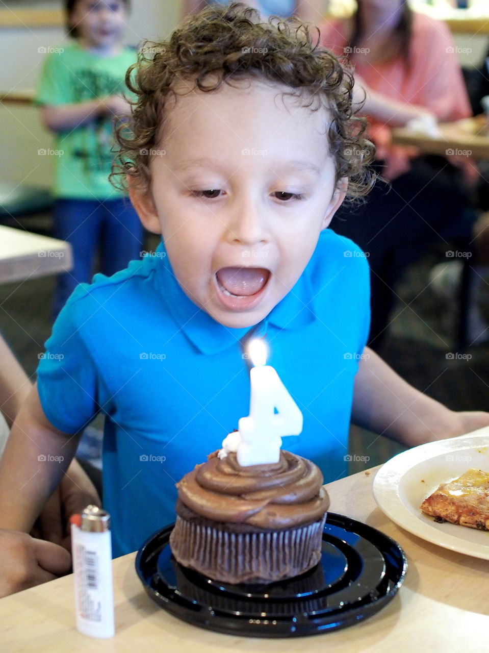 A little boy turns four and blows out the candle on his chocolate cupcake that he can’t wait to dig into. 