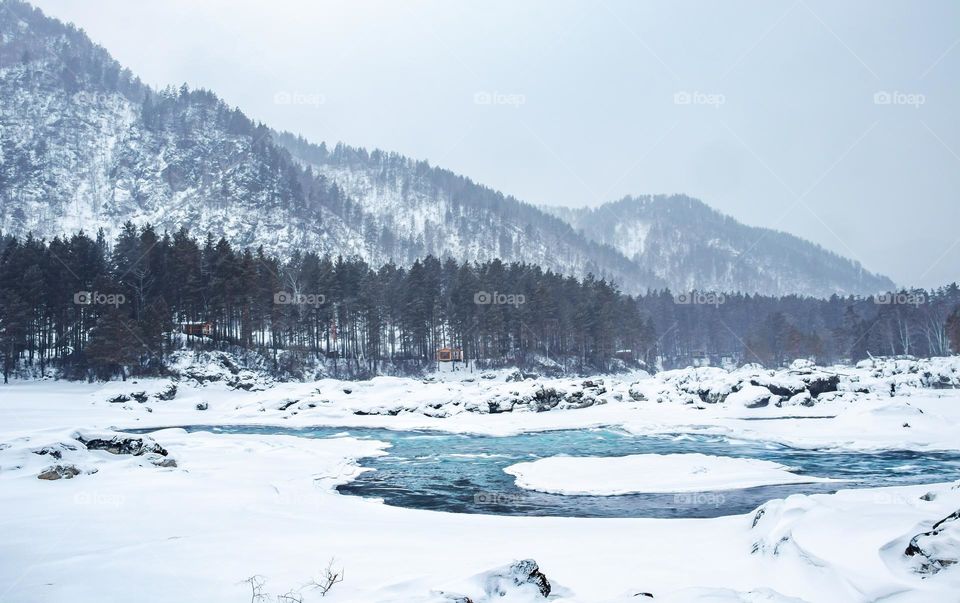Winter landscape with icy lake and snowy mountains 